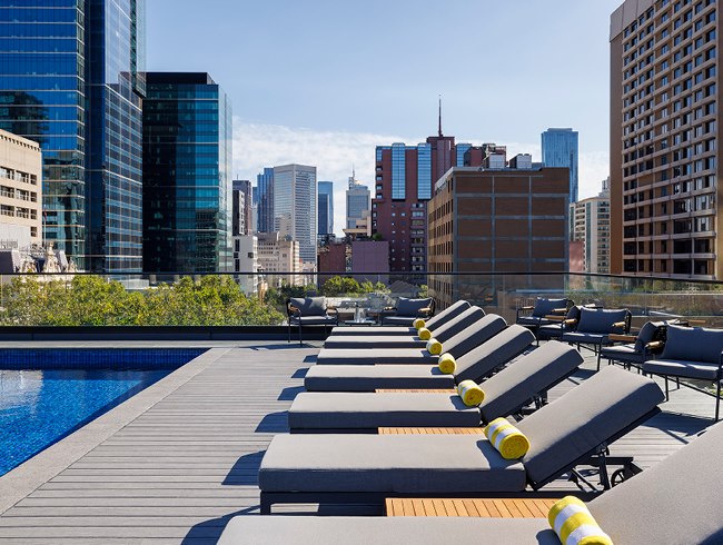 Sun loungers and the heated pool at LE SPLASH rooftop terrace with city views